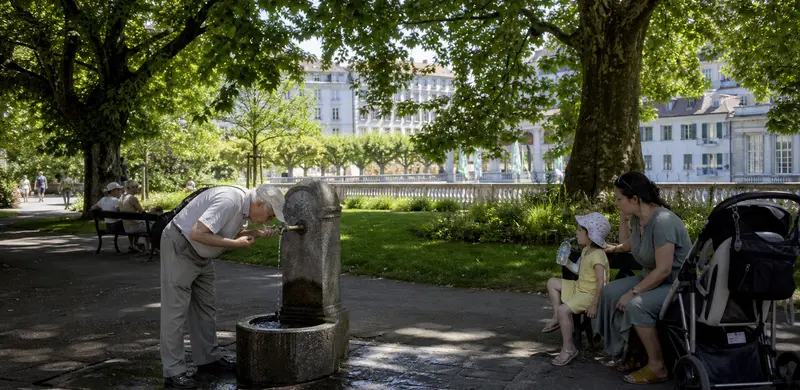 Parc urbain ombragé avec une fontaine publique pendant une journée chaude